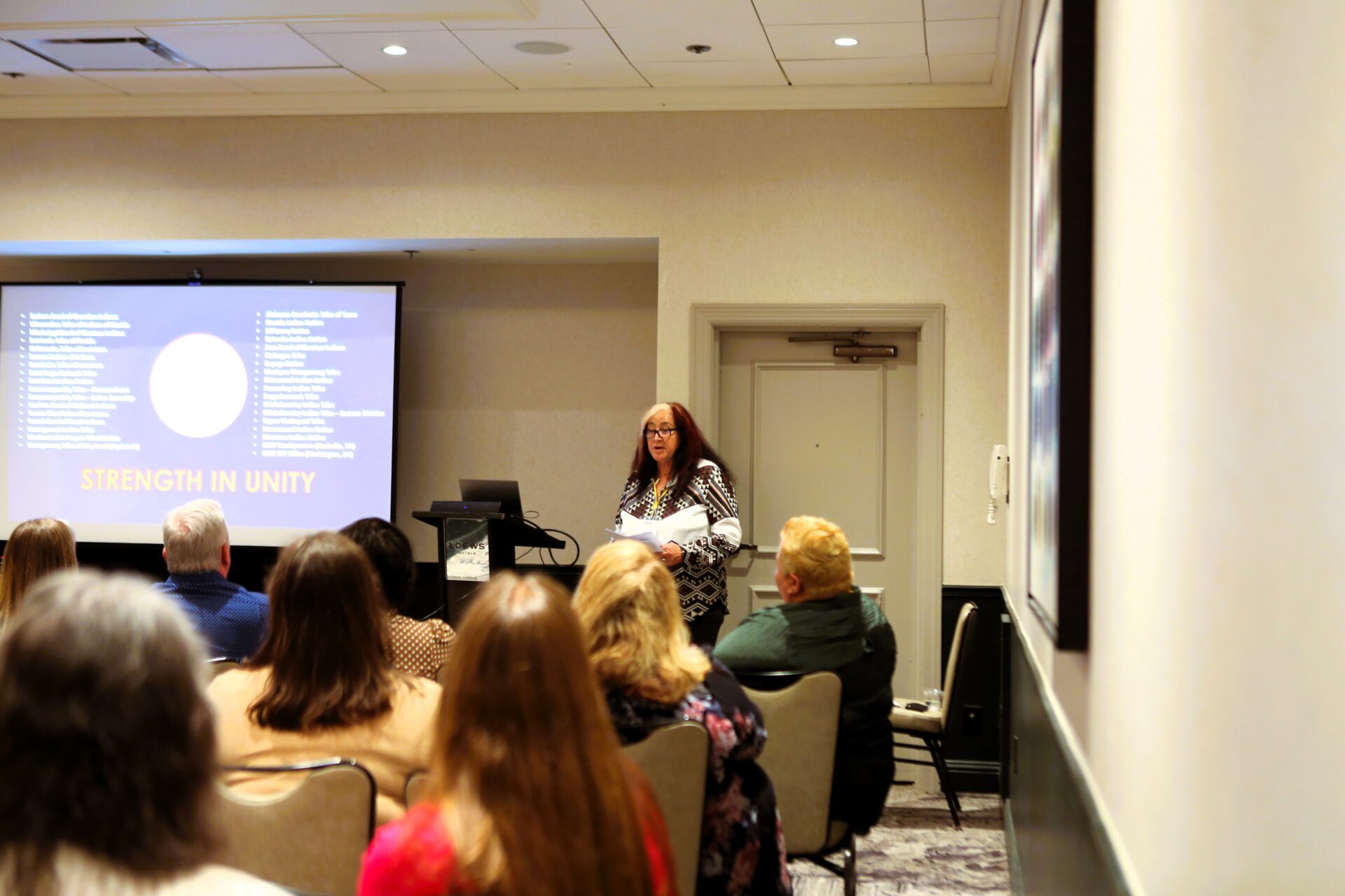 Woman presenting a slideshow to an attentive audience in a conference room.