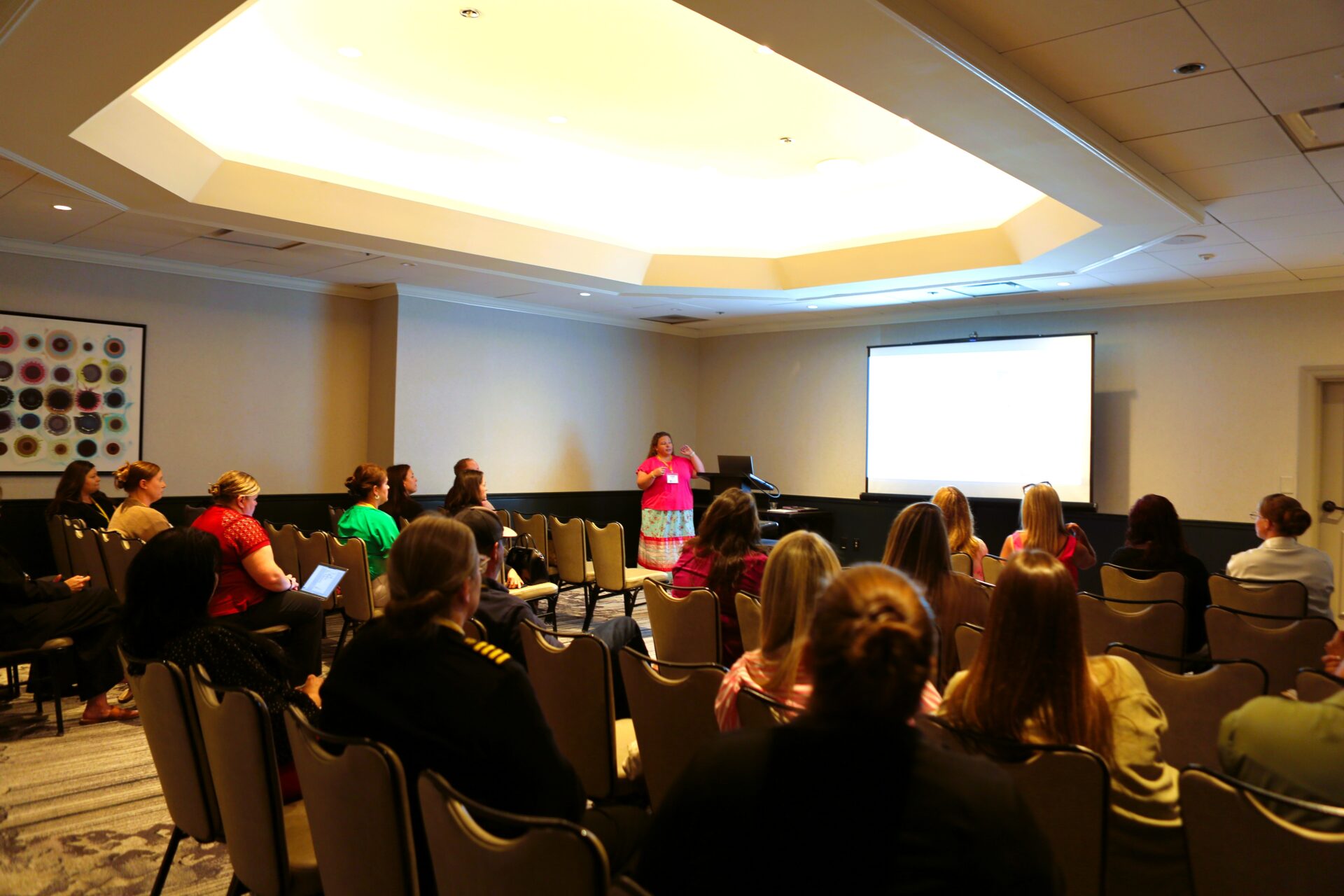 Speaker presenting to an attentive audience in a conference room.