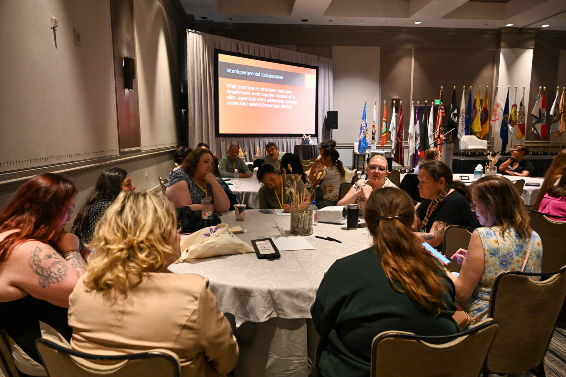 Group of people engaged in a focused discussion around a round table in a conference room.
