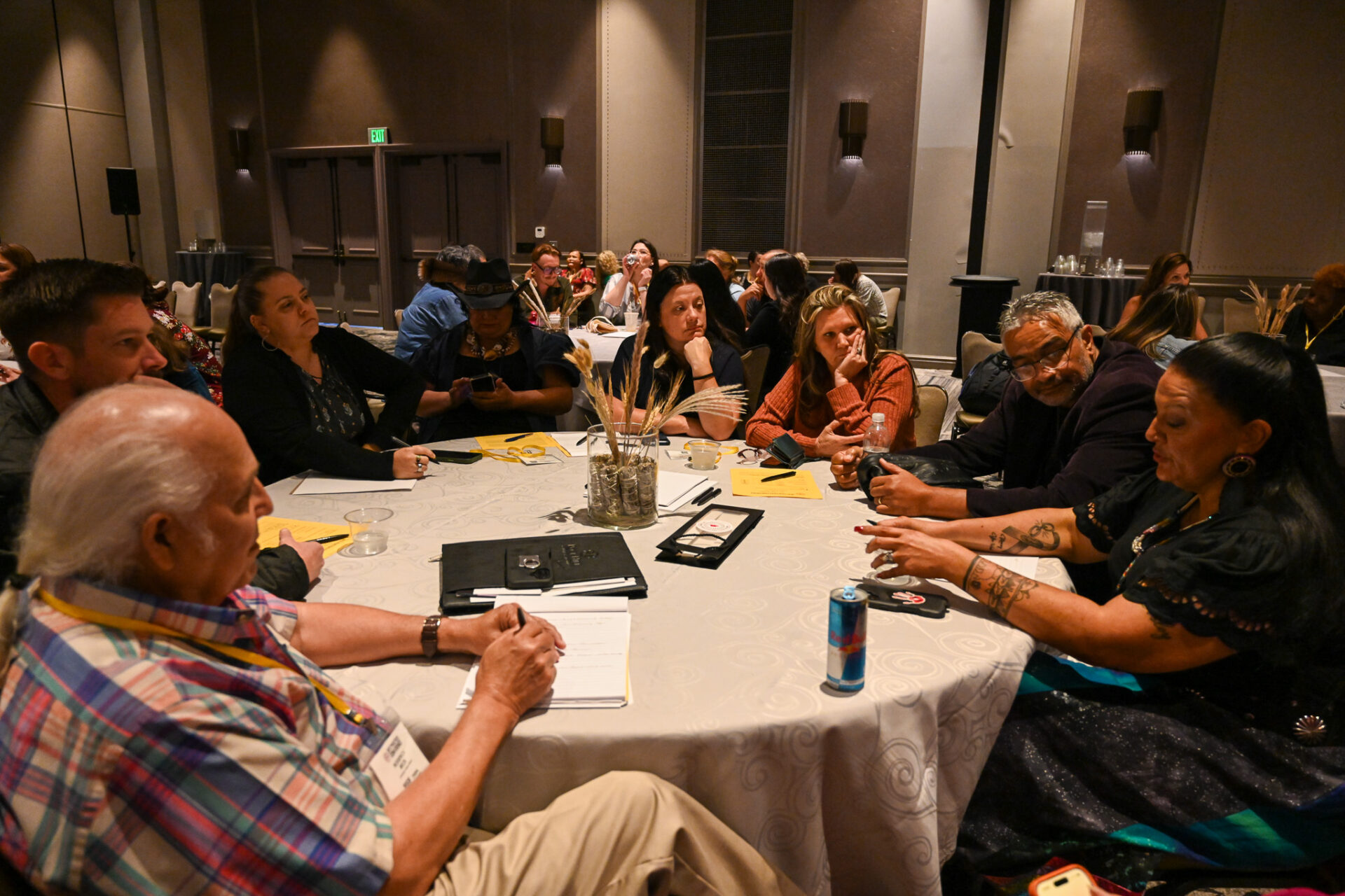 Group of people engaged in a focused discussion around a round table in a conference room.